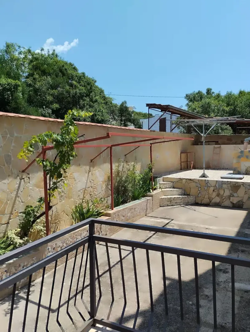 Dvorište kuće sa popločanim dijelom i ogradom.