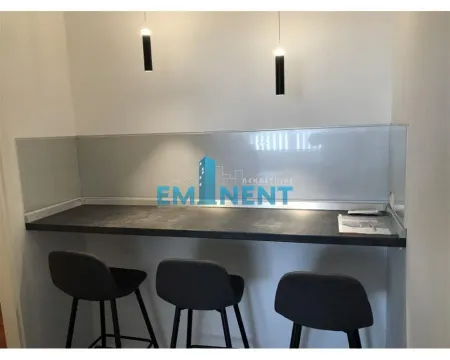Small kitchen with a bar counter and bar stools. - image 10