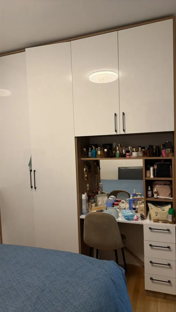 Spavaća soba sa velikim bijelim plakarom i toaletnim stočićem.