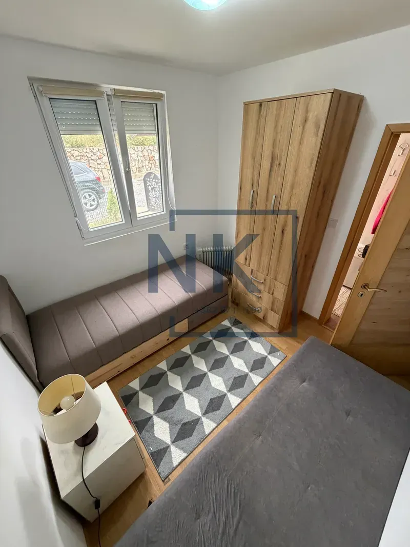 Small bedroom with two beds, a wardrobe, and a window.