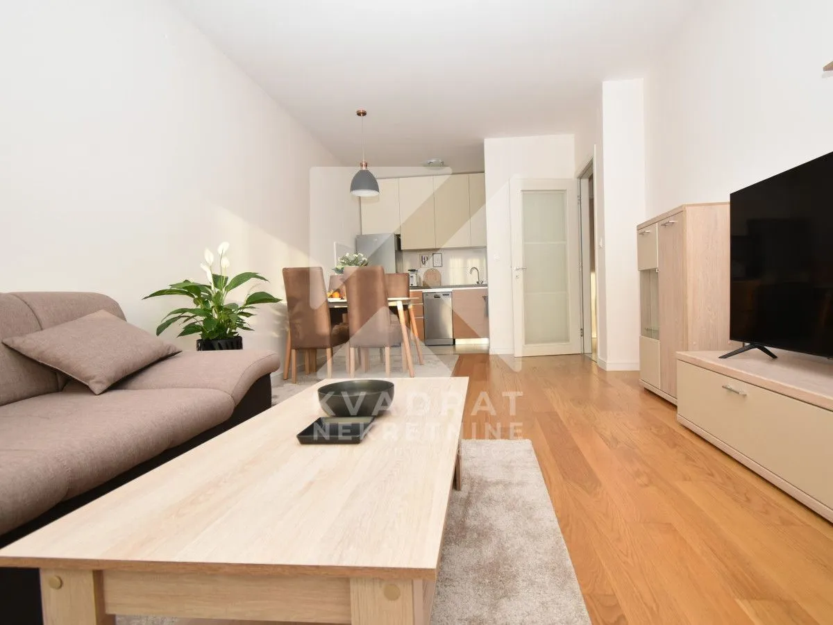 Living room with a sofa, TV, and an adjoining dining area.