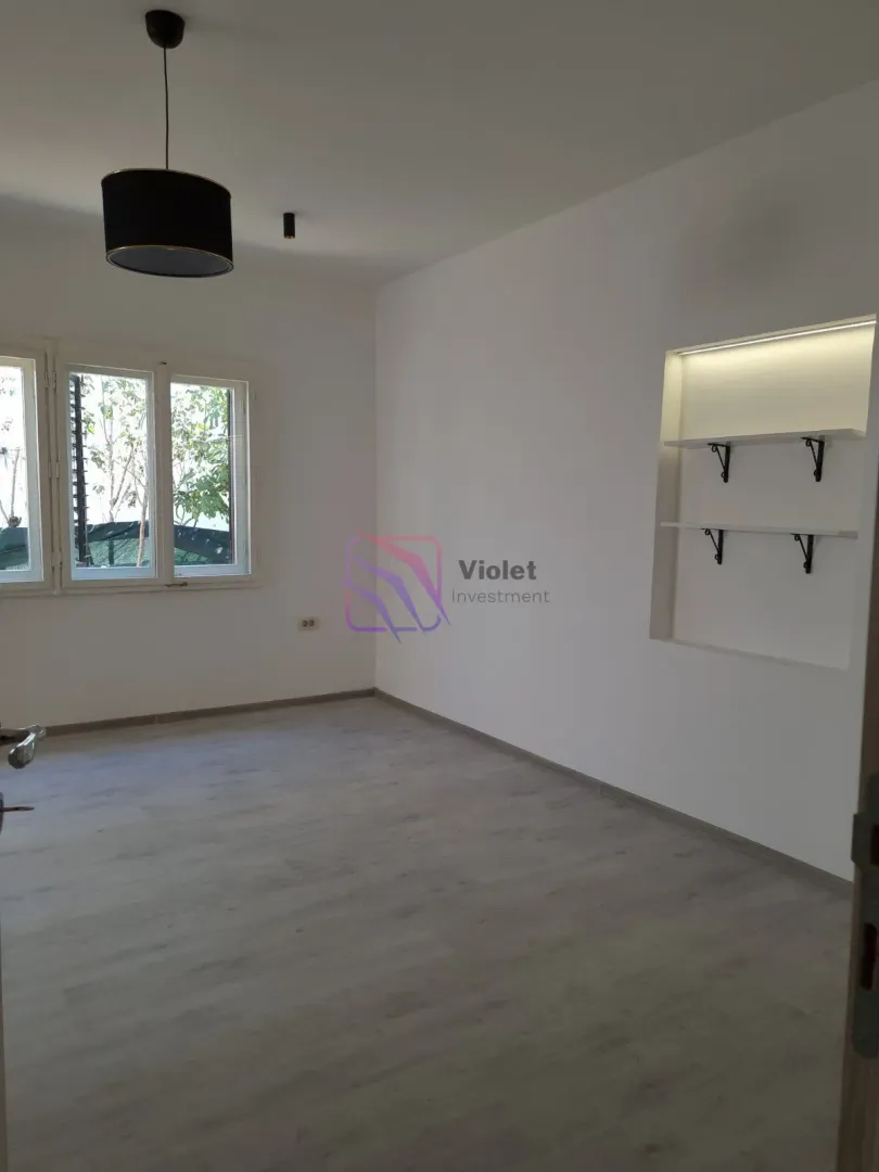 Empty bright room with a window, laminate flooring, and built-in wall shelves.