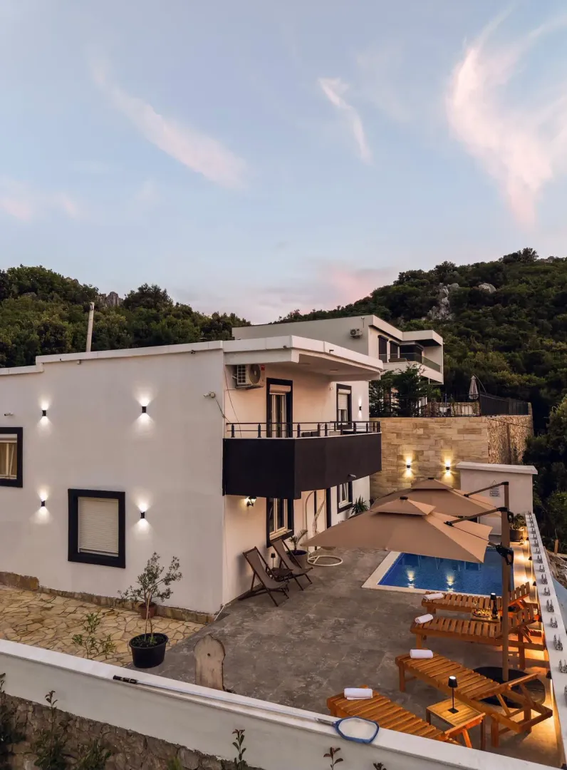 Exterior of the house with a swimming pool and sun loungers in the yard.