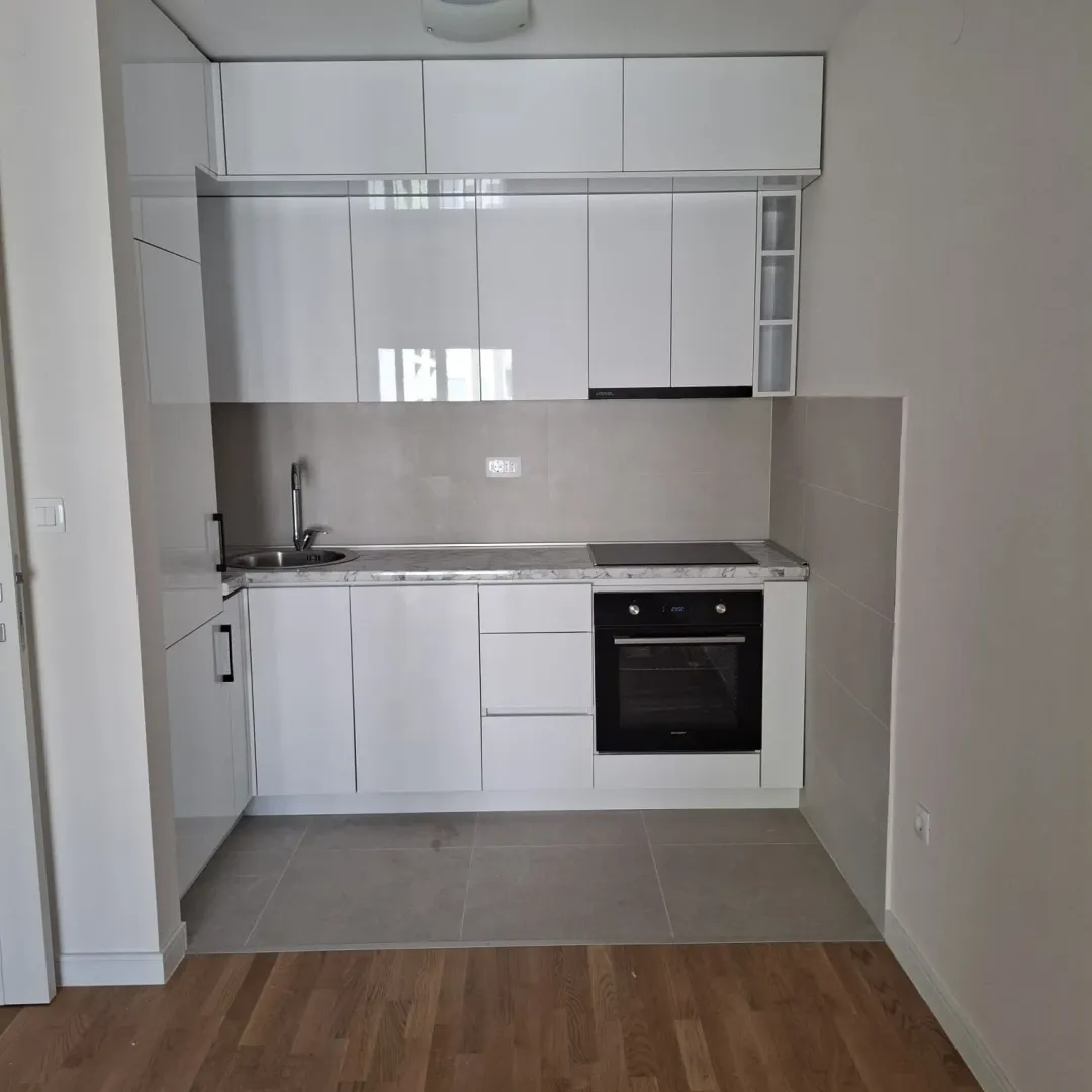 Modern white kitchen with built-in oven and sink.