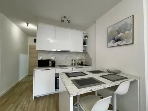 Small kitchen with white cabinets and a dining table with chairs. - image 7
