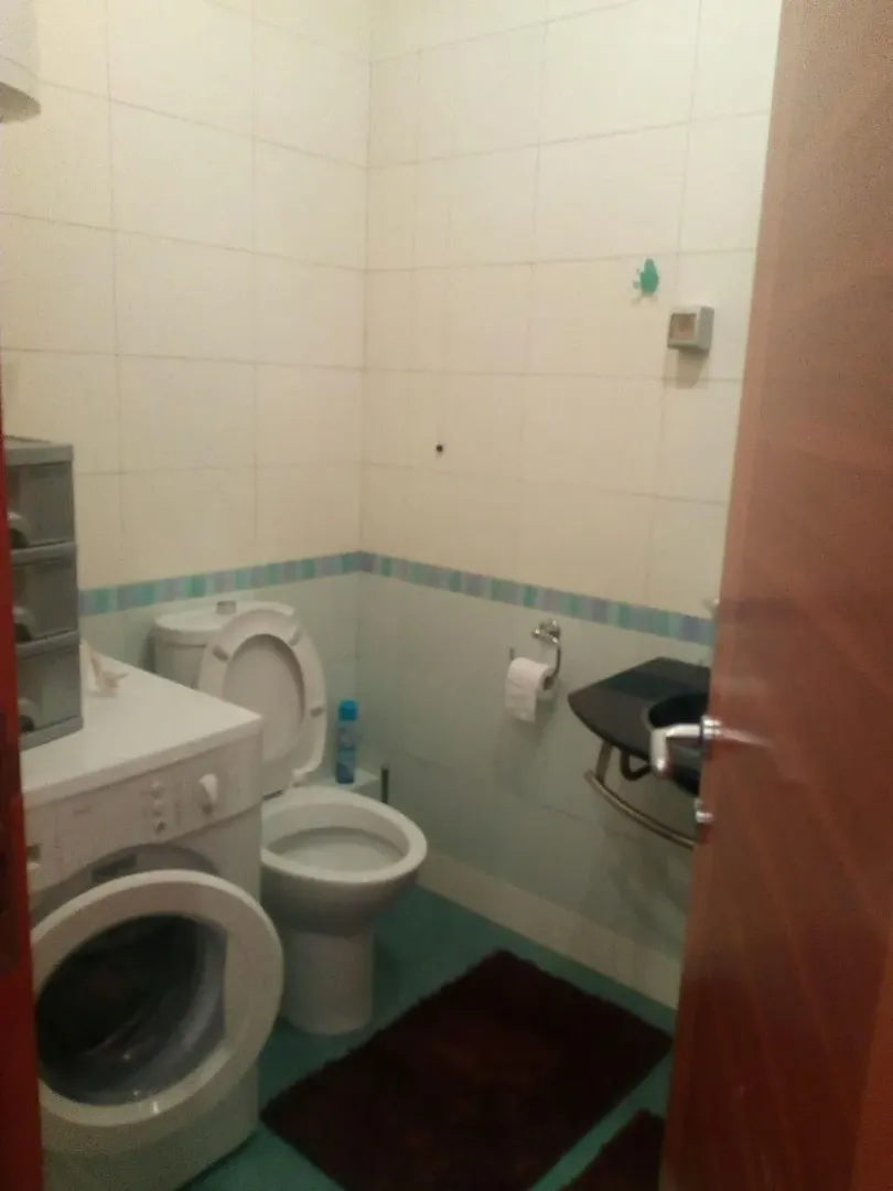 A small bathroom with a washing machine and a toilet.