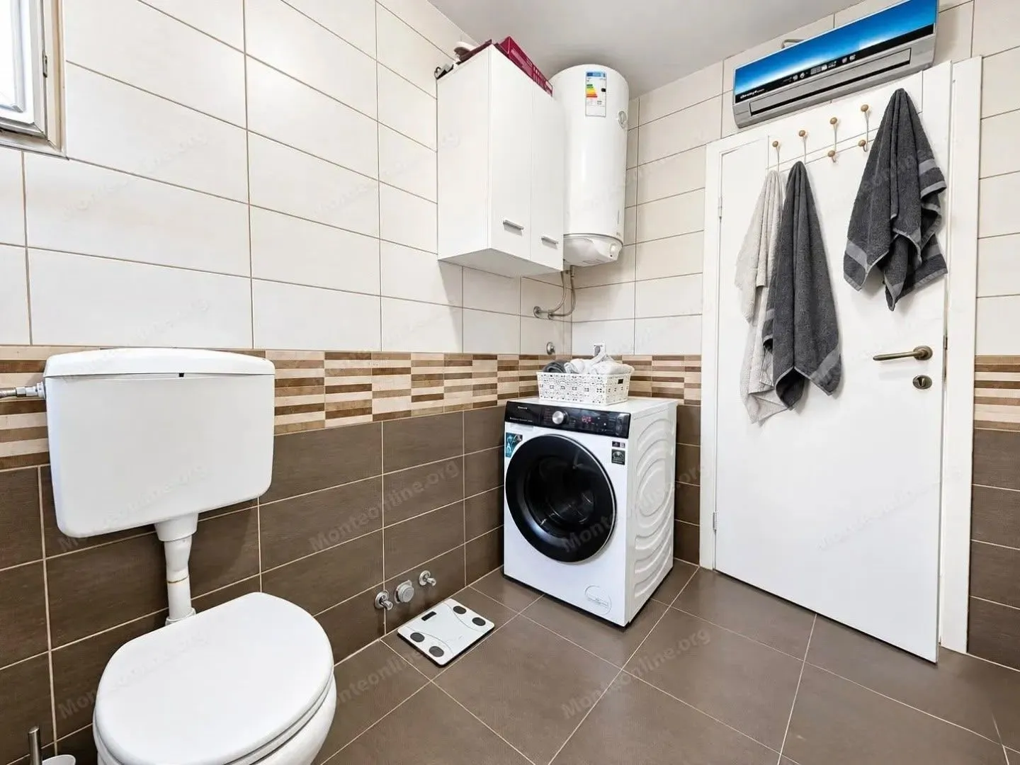 Kompaktno kupatilo sa WC šoljom, mašinom za veš i bojlerom.