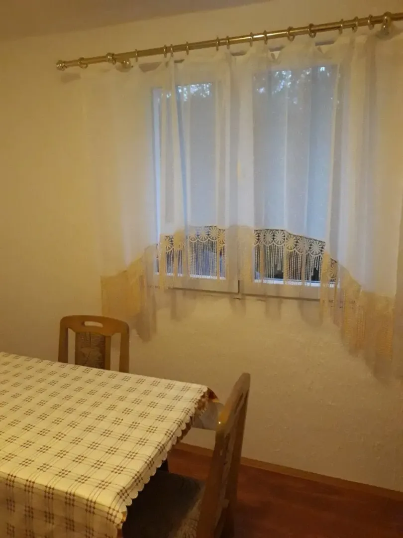 Trpezarijski sto sa stolicama pored prozora sa zavjesama.