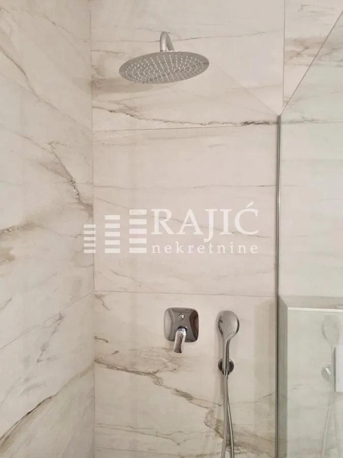 Modern walk-in shower with marble-look tiles and built-in fixtures.