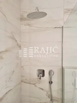 Modern walk-in shower with marble-look tiles and built-in fixtures. - image 7