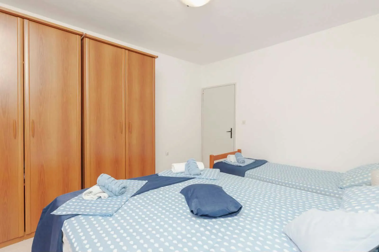 Bedroom with two beds and a large wooden wardrobe.