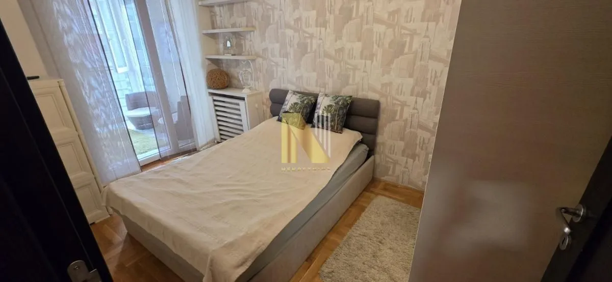 Nameštena spavaća soba sa bračnim krevetom i izlazom na terasu.