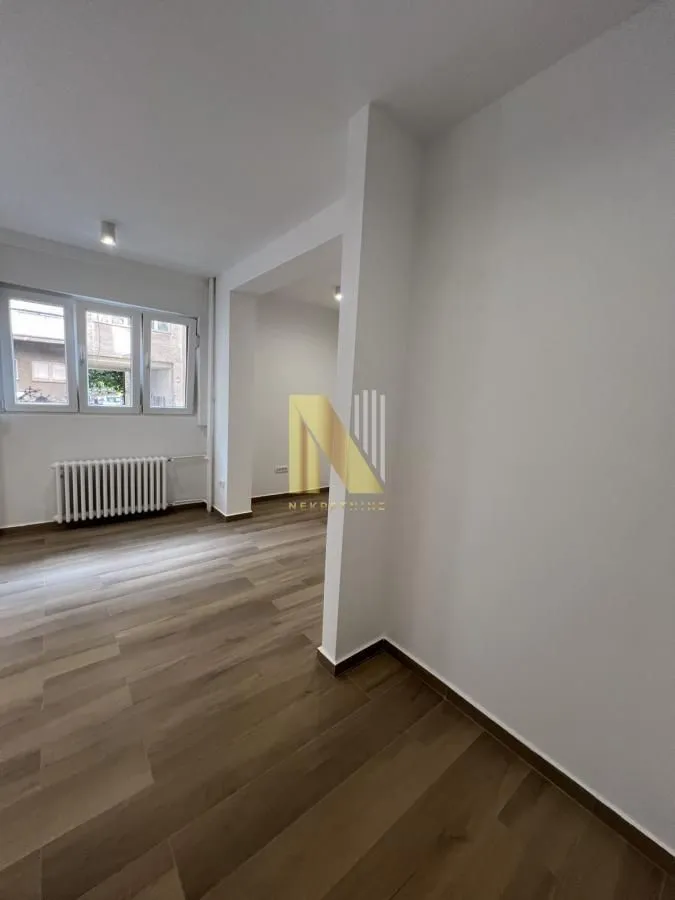Empty living room with wooden flooring and white walls.