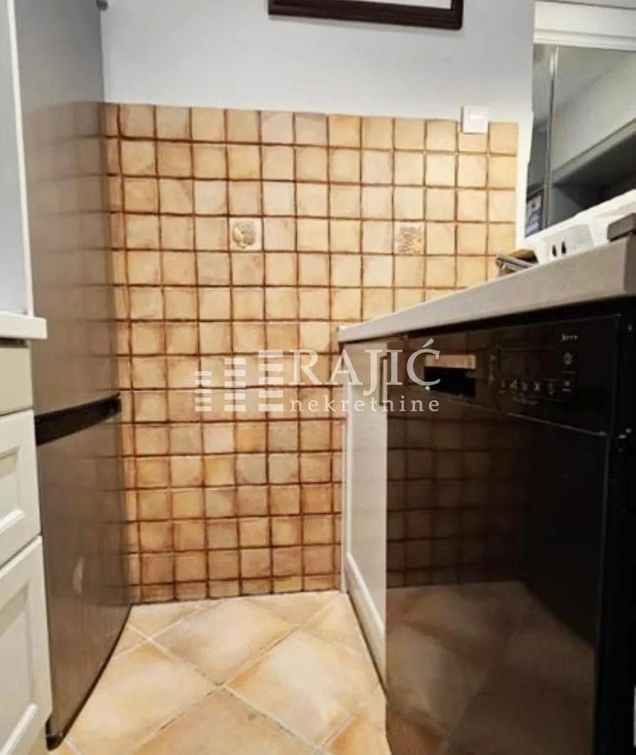 Smaller kitchen with cabinetry and ceramic wall tiles.