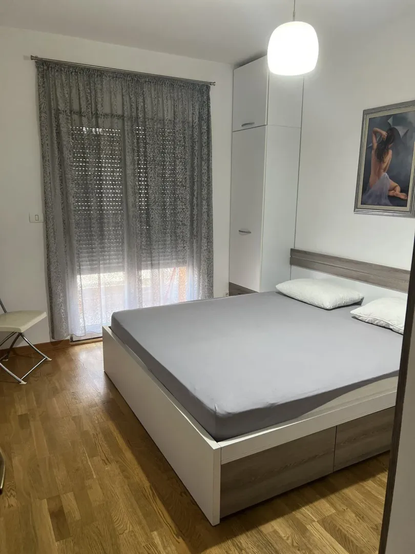 Jednostavno namještena spavaća soba sa bračnim krevetom i ormarom.