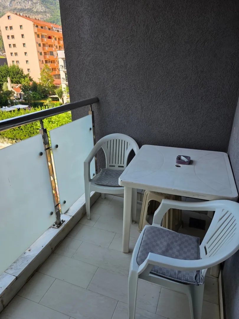 Manji namješteni balkon sa stolom, stolicama i pogledom na okolne zgrade.