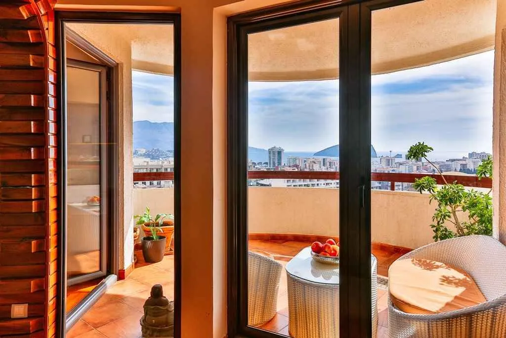 View of a spacious terrace and the sea through large glass doors.