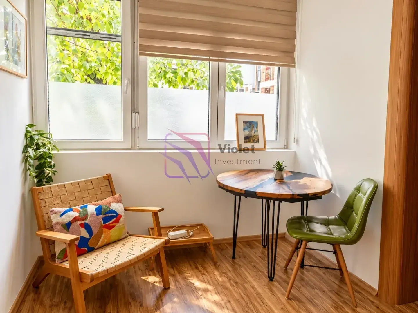 Sitting corner with a table, armchair, and green chair by the window.