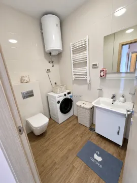 Compact bathroom with a sink, washing machine, and wall-mounted water heater. - image 12