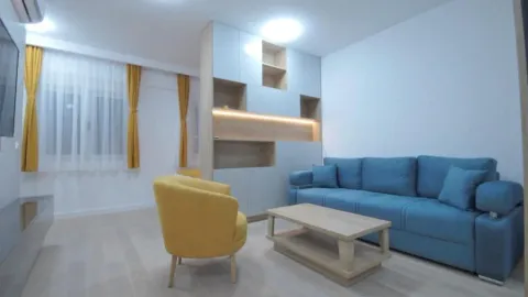 Living room with a blue sofa, a yellow armchair, and built-in shelving units. - image 9