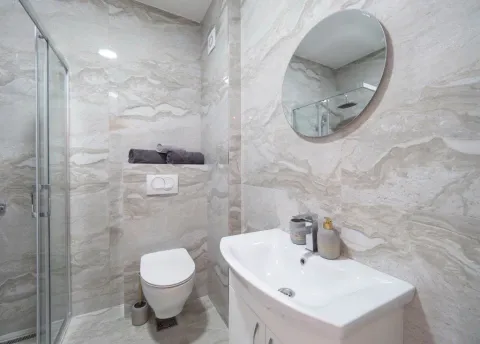 Modern tiled bathroom with a shower cabin, washbasin, and toilet. - image 9