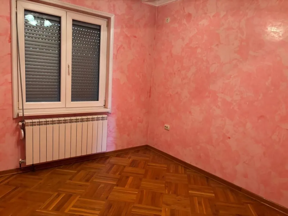 Empty room with pink walls and wooden parquet flooring.