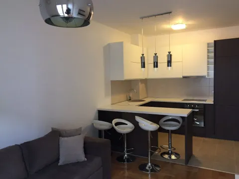 Compact kitchen with a breakfast bar and bar stools opening into the living area. - image 5