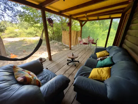 Covered wooden terrace with seating furniture and a yard view. - image 12