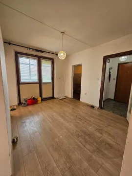 Prazna soba sa drvenim podom, prozorom i vratima koja vode u hodnik. - image 3