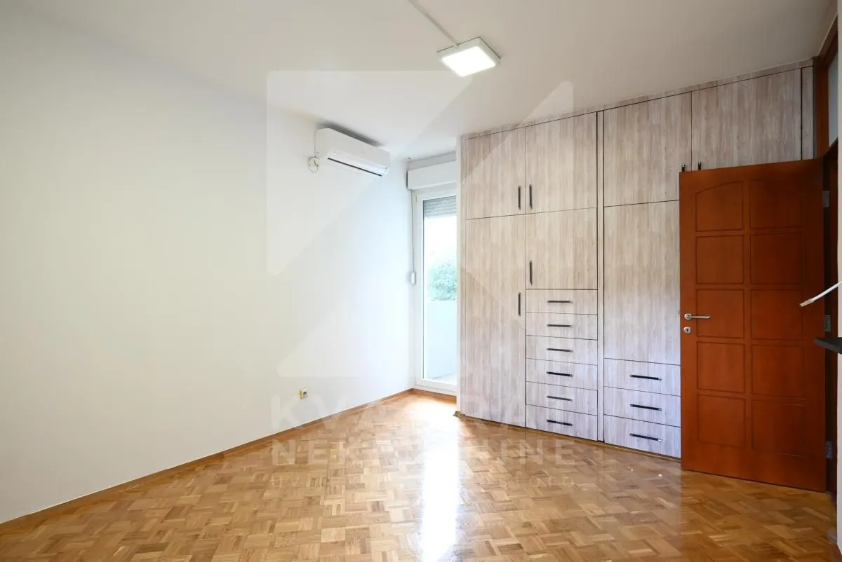 Empty room with built-in wardrobe, wooden parquet flooring, and air conditioning.