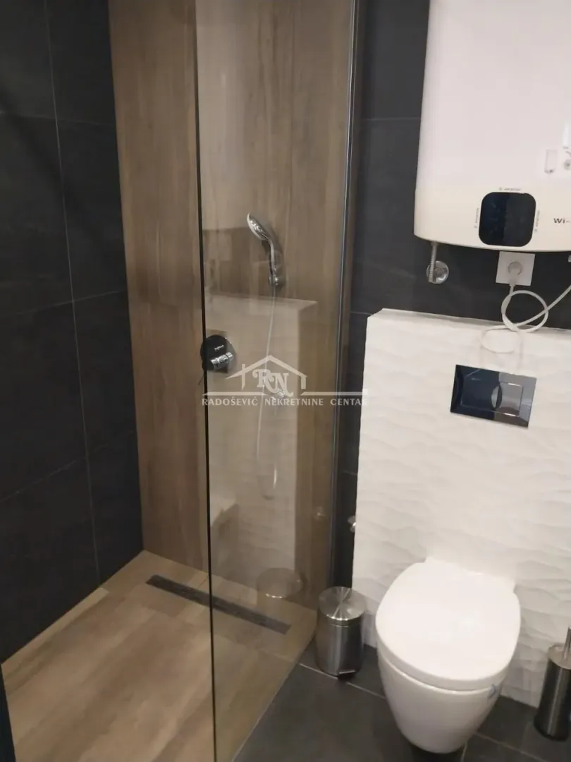 Moderno kupatilo sa tuš kabinom i ugradnom wc šoljom.