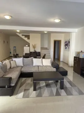 Living room with a sectional sofa, coffee table, and dining area in the background. - image 7