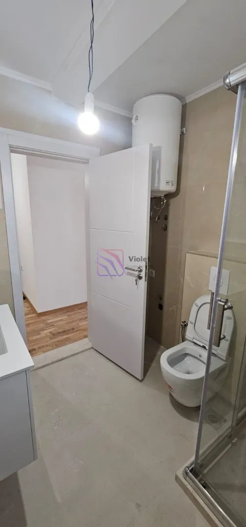 Pogled na kupatilo sa WC šoljom, tuš kabinom i bojlerom.