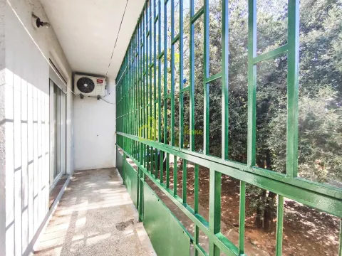 Dugačak balkon sa zelenom zaštitnom ogradom i pogledom na drveće. - image 9