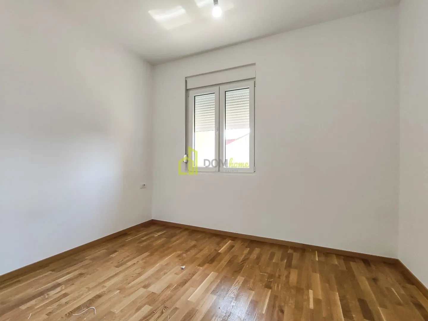 Prazna soba sa bijelim zidovima i drvenim podom.