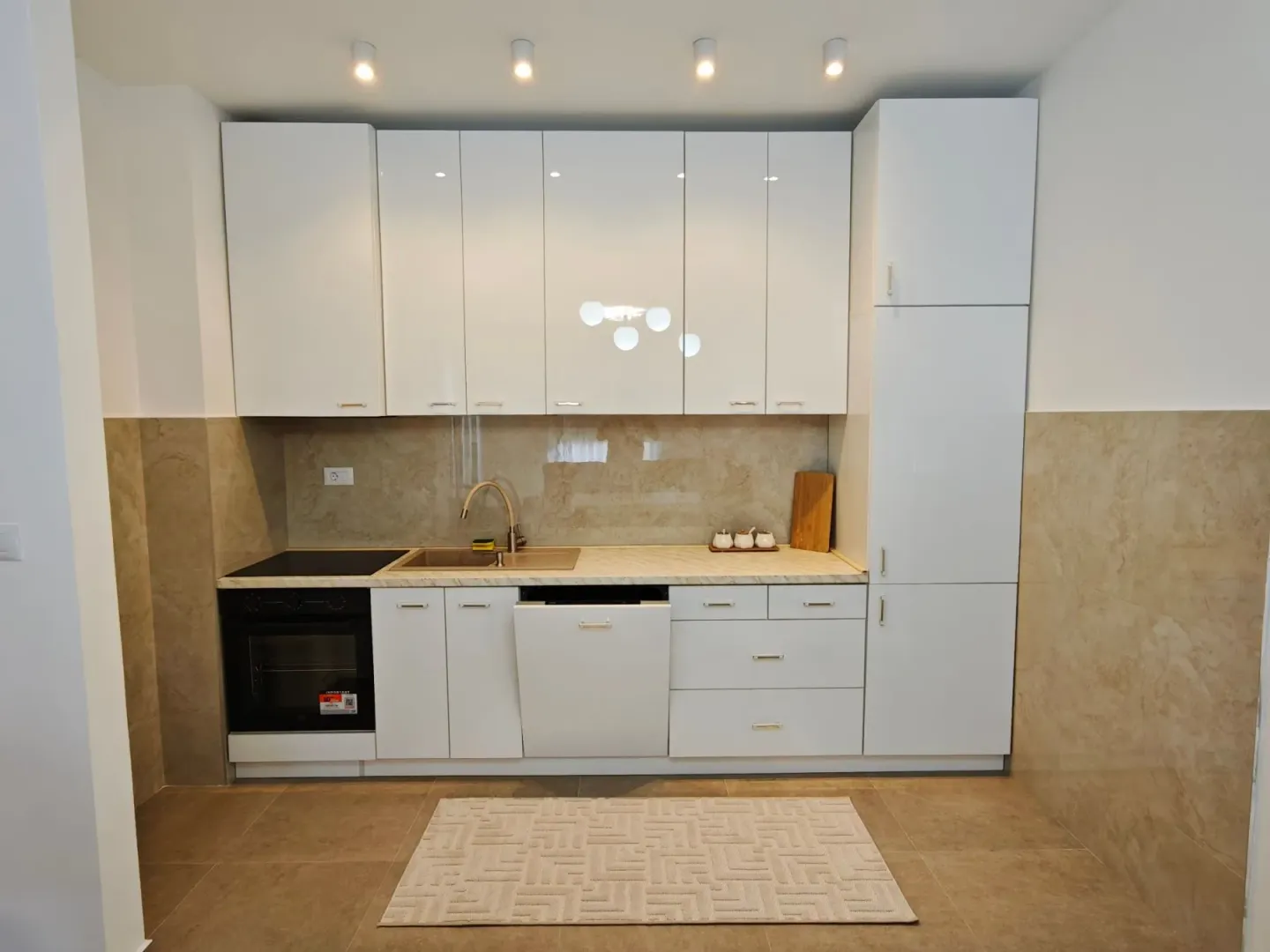 Modern white kitchen with built-in appliances and a sink.