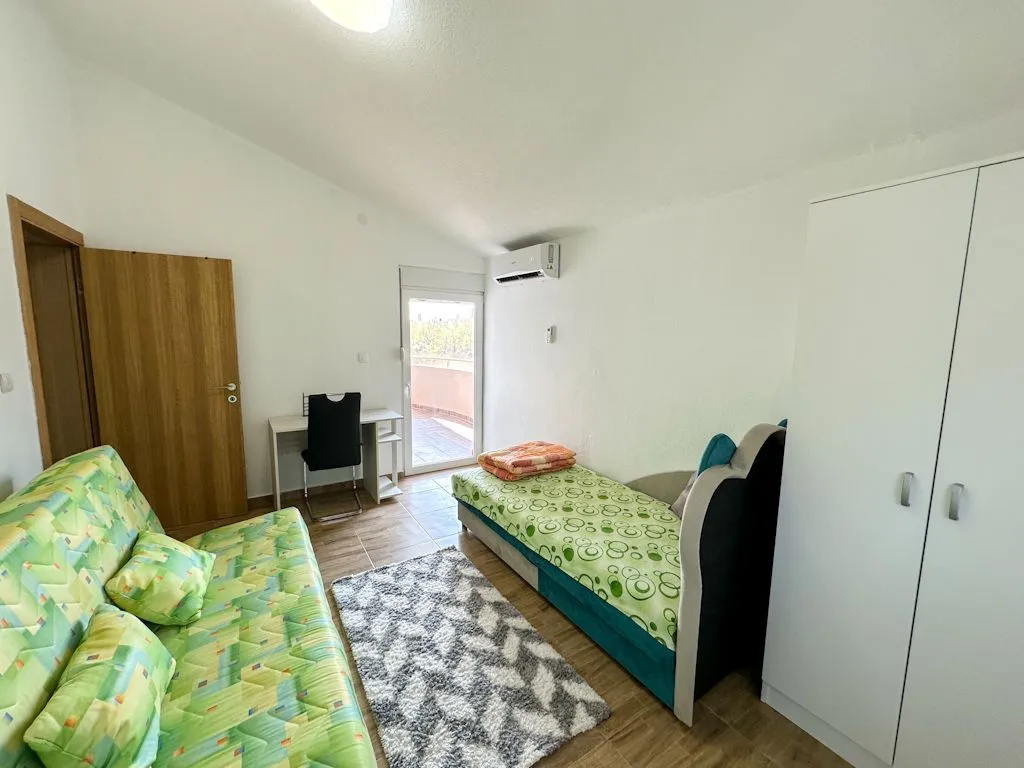 Namještena spavaća soba sa krevetom, garderoberom i izlazom na terasu.