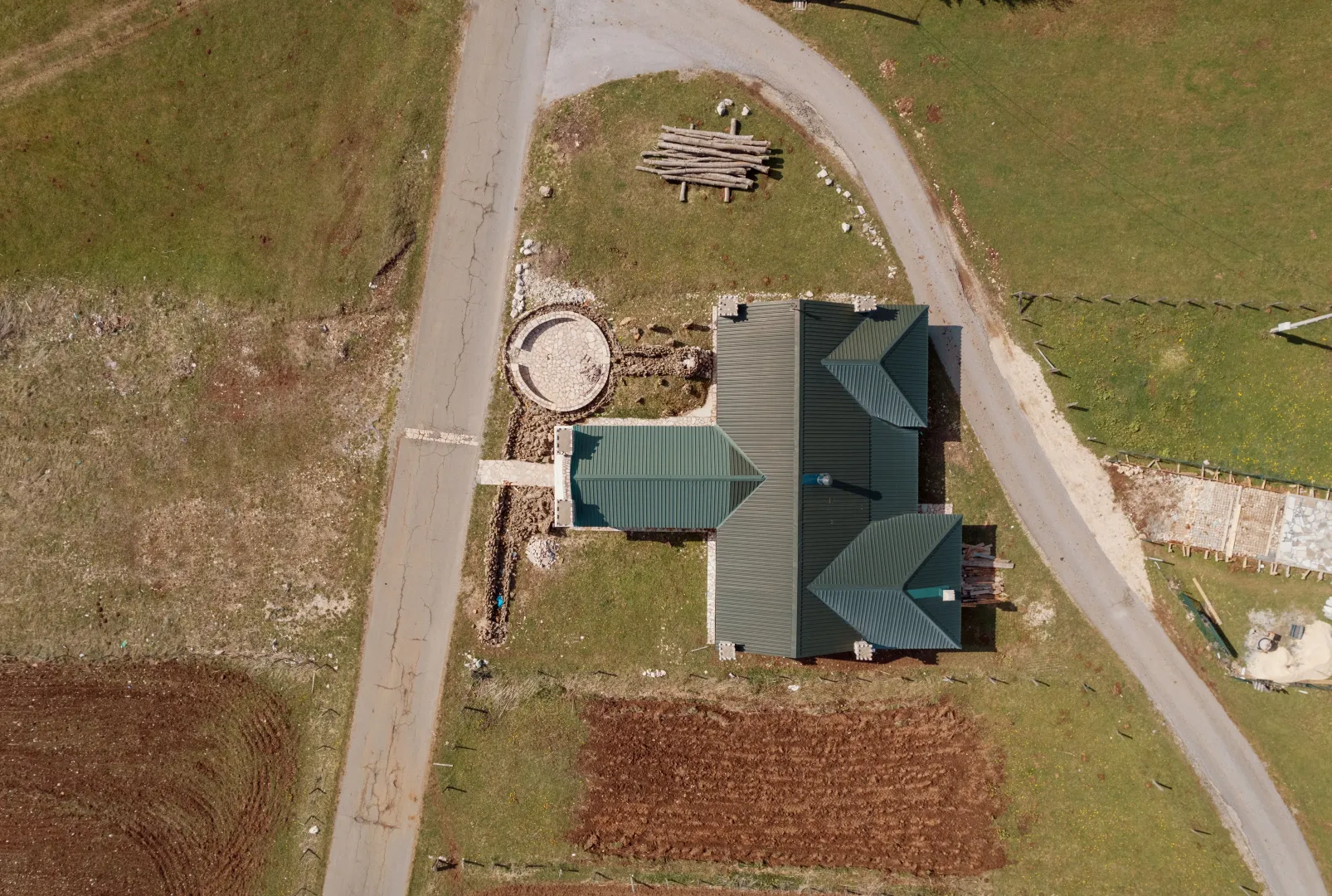 Aerial view of a house with a green roof and surrounding property.
