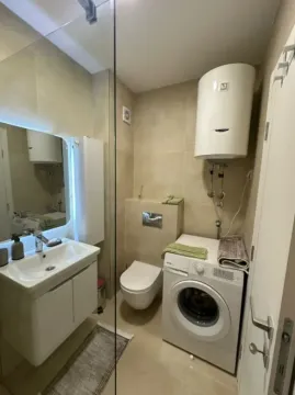 Small bathroom with a sink, toilet, washing machine, and water heater. - image 6