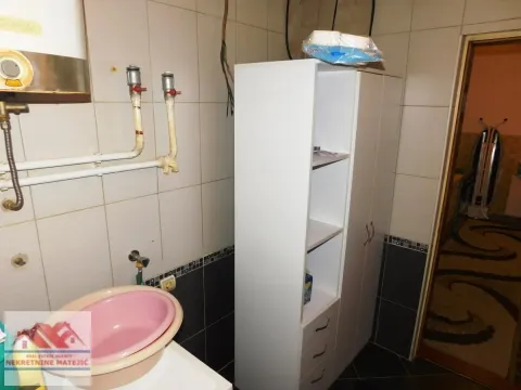 Manje kupatilo sa belim ormarićem, umivaonikom i pločicama na zidovima. - image 18