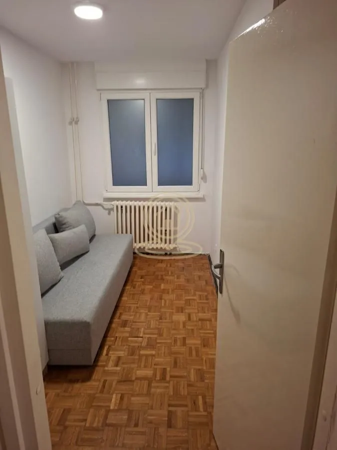 Manja soba sa krevetom na razvlačenje i parketom na podu.