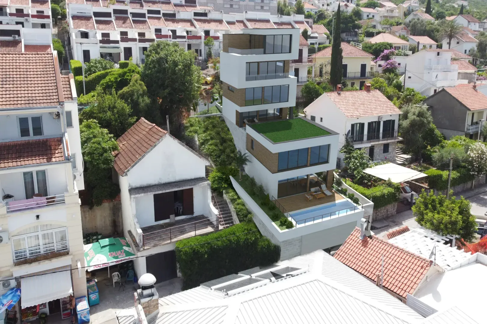 Pogled iz vazduha na modernu višespratnu zgradu u izgradnji okruženu naseljem.