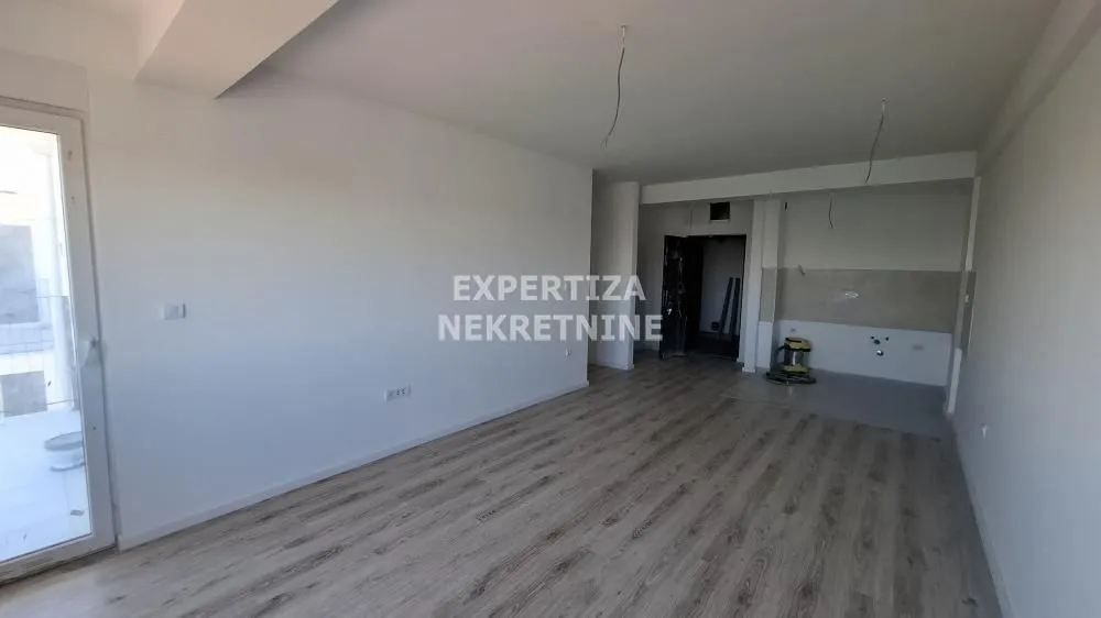 Empty living room with laminate flooring and access to the terrace.