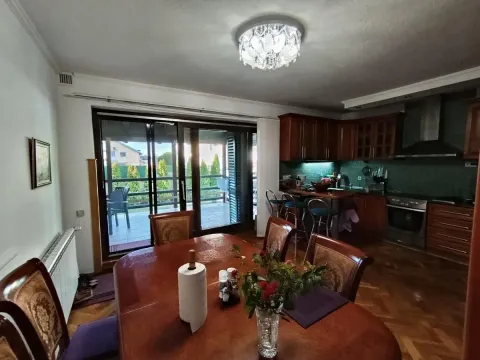 Trpezarija sa drvenim stolom i pogledom na terasu, povezana sa kuhinjom. - image 37