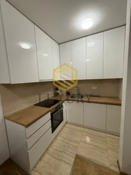 Moderna bijela kuhinja sa drvenom radnom pločom i ugradnim elementima. - image 3
