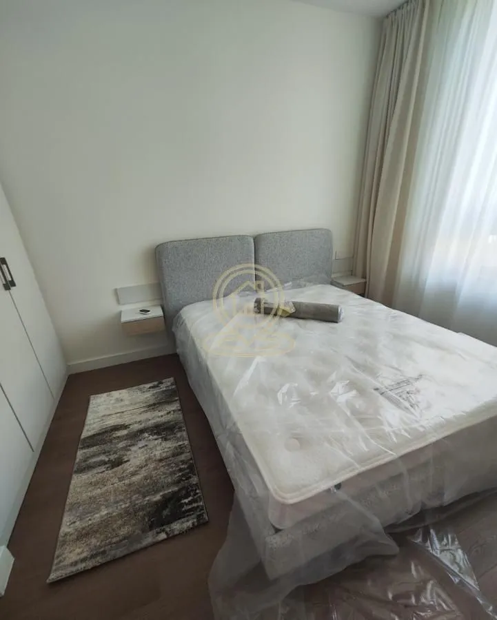 Bedroom with a double bed covered in protective film.
