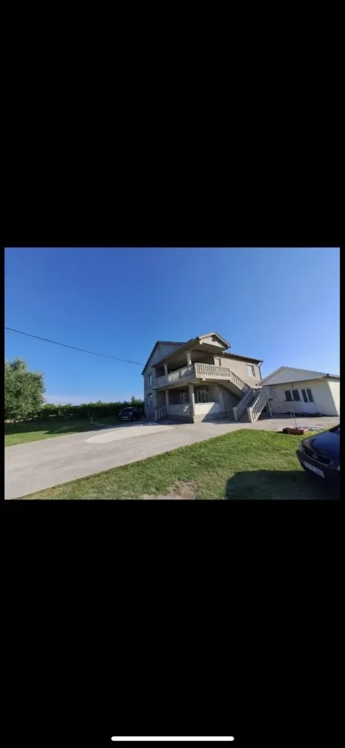 Dvospratna kuća sa prostranim dvorištem i prilazom pod vedrim nebom.
