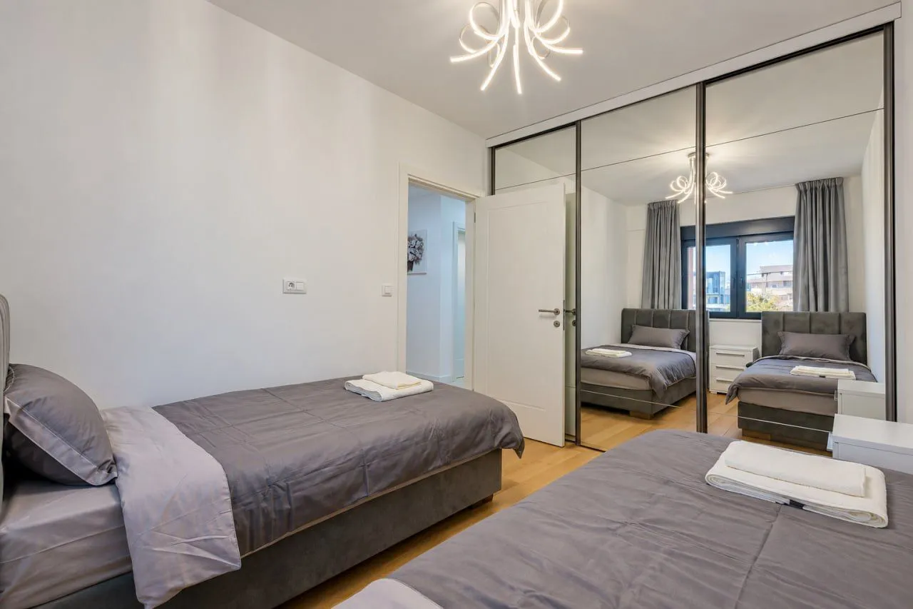 Modern bedroom with two single beds and a mirrored built-in wardrobe.