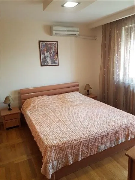 Svijetla spavaća soba sa bračnim krevetom i noćnim ormarićima.