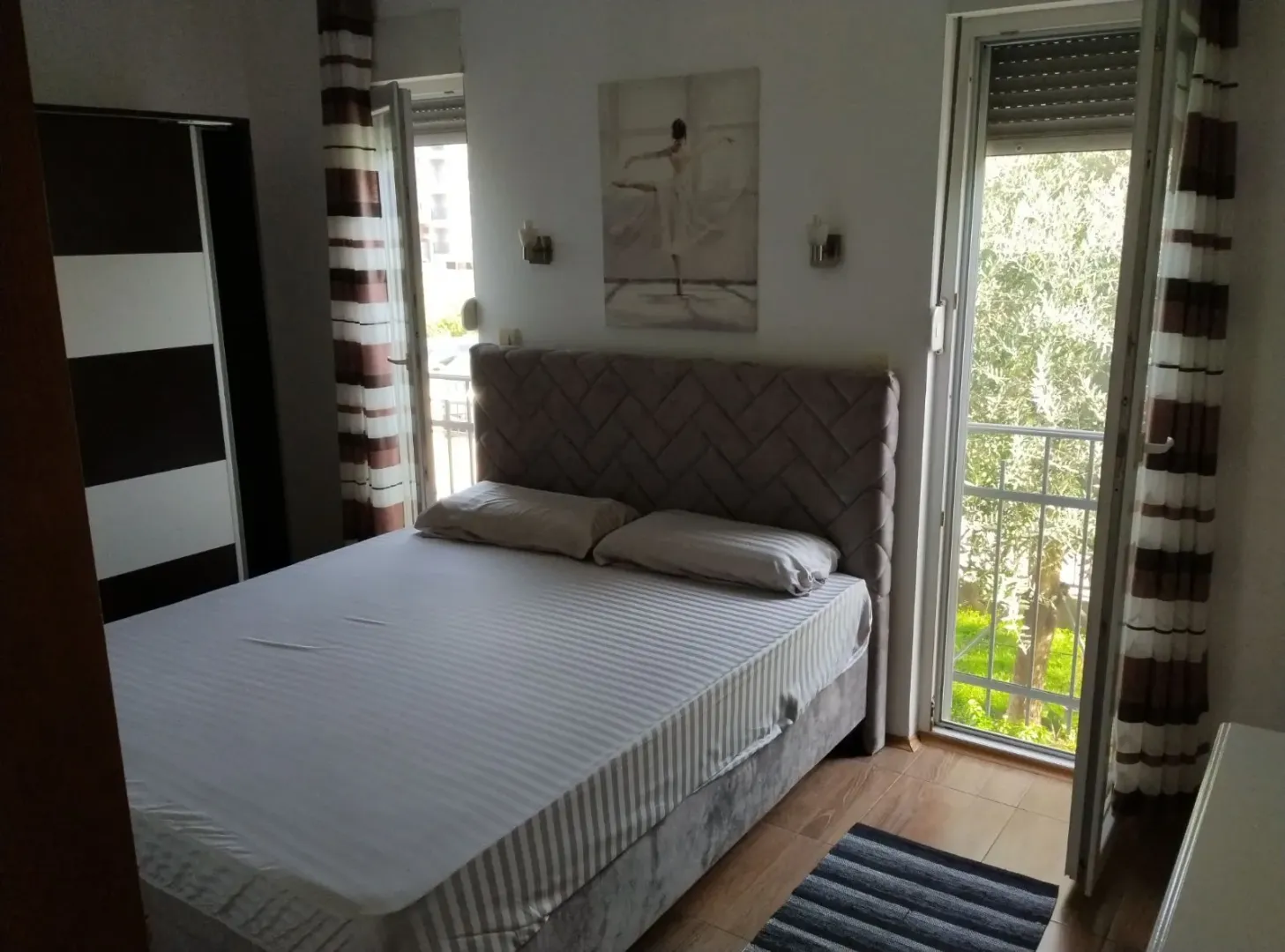 Svijetla spavaća soba sa bračnim krevetom i izlazom na balkon.